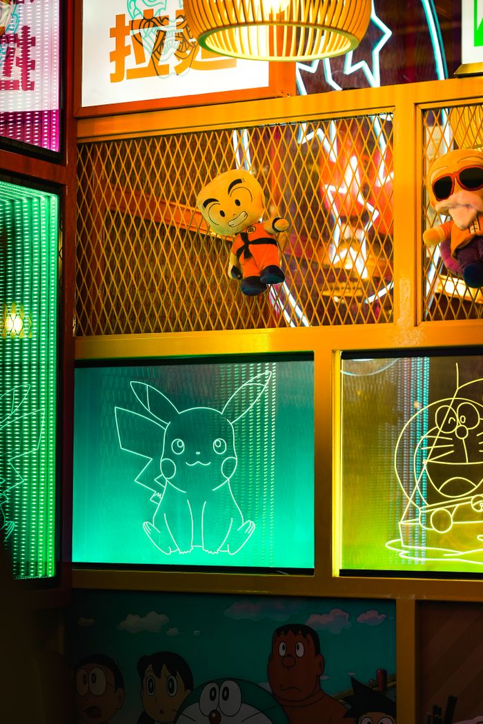 A vibrant and colorful anime-themed restaurant decor in Tokyo, featuring iconic neon signs and plush toys.