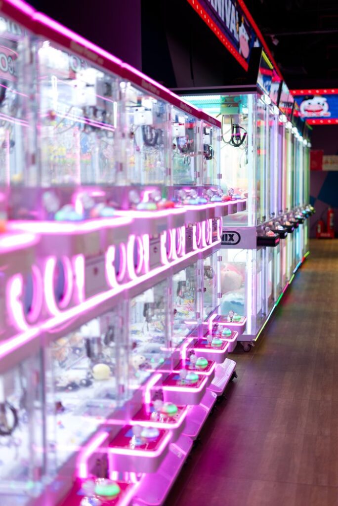 A brightly lit arcade featuring a row of vibrant claw machines indoors.