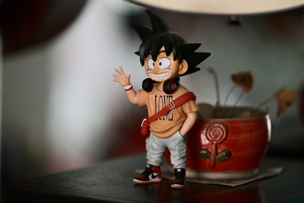 pexels-photo-38033784-38033784 Anime figurine with headphones, standing on a desk beside a colorful pot, indoors.